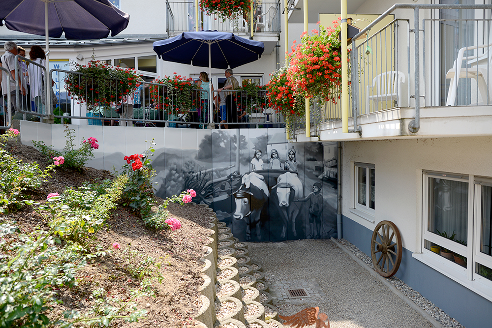 GRAFFITI-KÜNSTLER ODENWALD: Blick auf die fertige Wand von der Terrasse des Seniorenzentrums aus.  Malerische Umsetzung einer Straße in Limbach Anfang des zwanzigsten Jahrhunderts.