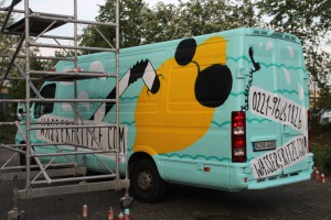 Fahrzeuggestaltung in Köln mittels Spray-Technik.Graffiti als Alternative zu Klebefolien. Abgebildet ist eine Zitrone mit Sonnenbrille, die im Wasser schwimmt. Der Hintergrund ist in Türkiestönen gehalten.