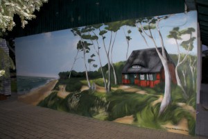 Graffiti-Sprayer Mecklenburg Vorpommern gestaltet Außenfassade bei Godewind Ferienwohnungen mit Ostseeküste als Bildmotiv.