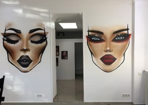 Graffitisprayer Düsseldorf: Gesichter gesprüht an einer Wand im Make-up-Studio